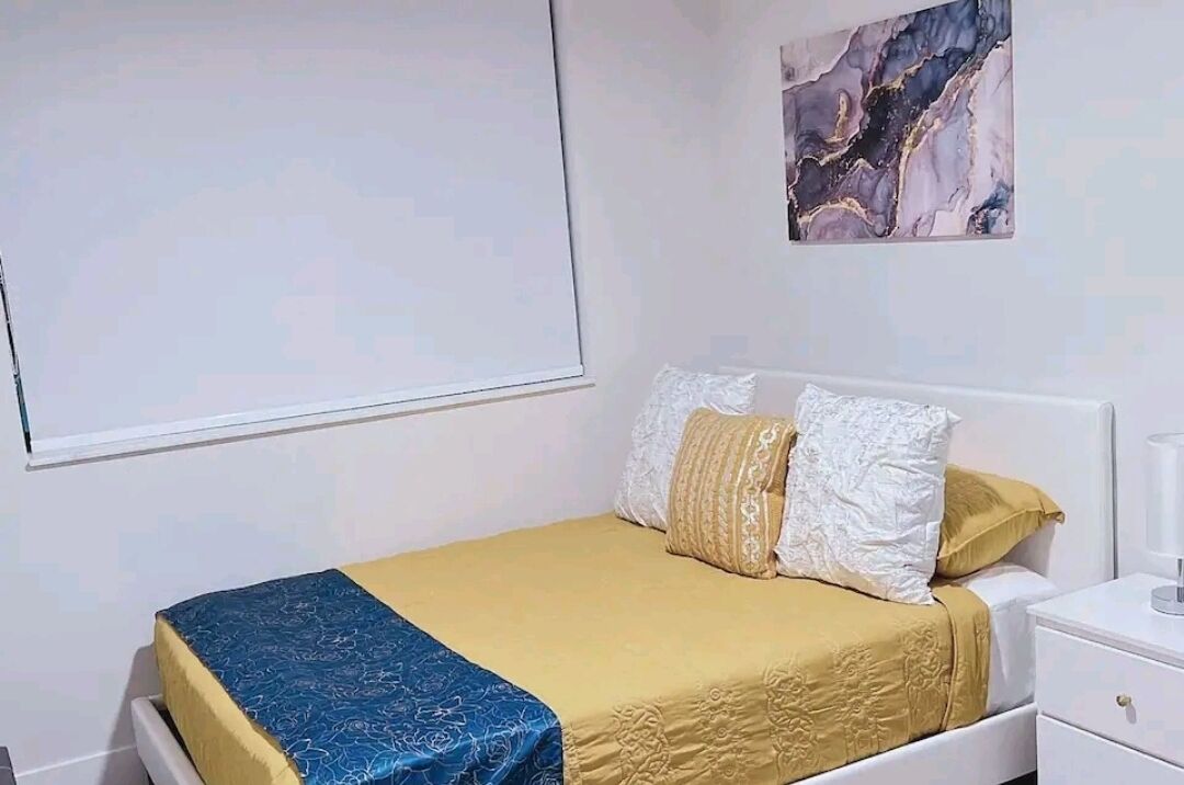 A bedroom with a bed, a nightstand, and a wall-mounted artwork.