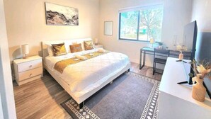 A bedroom with a bed, bedside tables, a desk, a chair, a ceiling fan, a window, and a television. - Lux and Cozy 2beds 2 Baths up to 8 guest (West Palm Beach)
