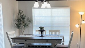 Een eethoek met een tafel, stoelen, een bankje, een plant in pot en een hanglamp.