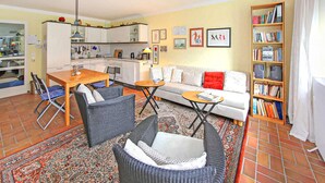 A compact living space with a kitchen, dining area, and a seating area with a sofa and chairs. - Ferienwohnung Prerow Ostseebad (Prerow (Ostseebad))