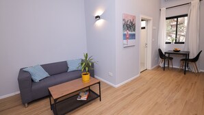 En moderne stue med en grå sofa, et træbord, en lille gul plante og et billede på væggen.