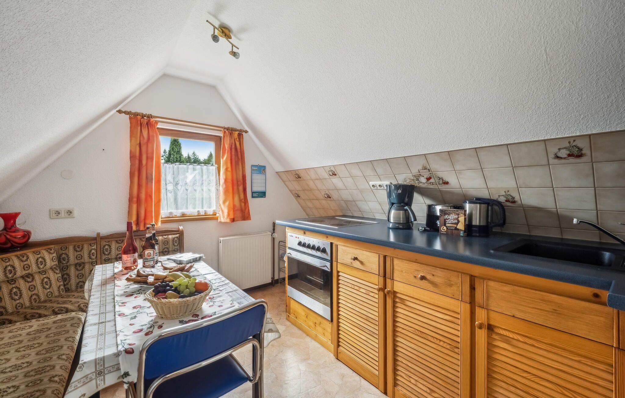 A cozy kitchen with a dining table set for two, a coffee maker, and a kettle on the counter.
