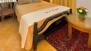 A hotel room with a bed, a chair, a small table with a vase, and a window with curtains. - Riad Dar Baddi Avec 9 Suite : Marrakech (Marrakech)