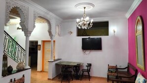 A living room with a dining area, a chandelier, a television, and traditional decor. - Riad Dar Baddi Avec 9 Suite : Marrakech (Marrakech)