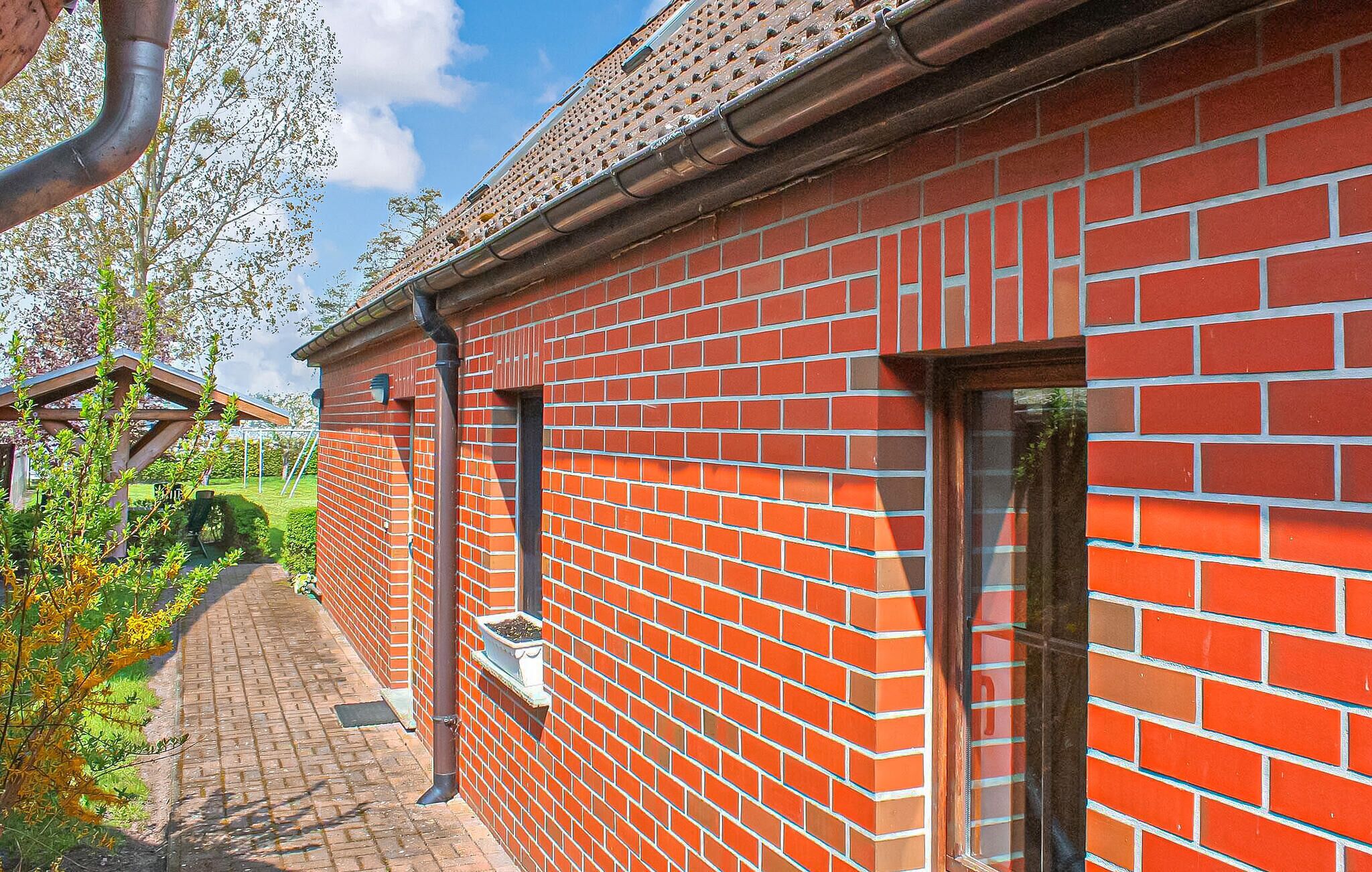 Ein Gebäude aus roten Ziegelsteinen mit einem Ziegeldach, einem Ziegelweg und einer Holzpergola.