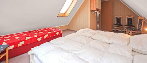 Een slaapkamer met een hoogslaper, een rode bank en een houten garderobe.