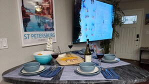 Een eettafel gedekt met blauwe borden, wijnglazen en een fles wijn, met een poster van St. Petersburg Florida aan de muur.