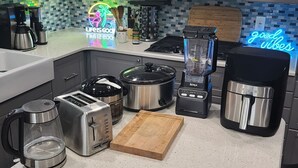Een keuken met een koffiezetapparaat, broodrooster, slowcooker, blender en een neonbord waarop staat: LIFE IS GOOD.