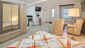 A modern bedroom with a bed, a wardrobe, a desk, a chair, a TV, and a window. - Ferienwohnung Hohen Sprenz (Hohen Sprenz)