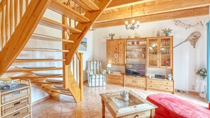 A wooden staircase leading to a living area with a sofa, a TV, and a cabinet with glass doors. - Stunning apartment in Stolpe/Usedom (Stolpe/Usedom)