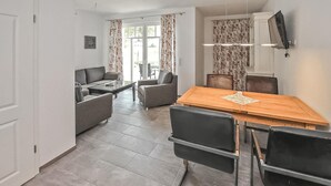 A modern living room with a sofa, chairs, a dining table, and a TV mounted on the wall. - 1 bedroom awesome apartment in Userin (Userin)