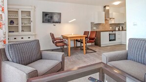 A modern living room with a sofa set, a wooden dining table, and a kitchen area with a stove and cabinets. - 1 bedroom awesome apartment in Userin (Userin)