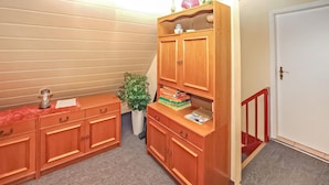Een kleine kamer met een houten kastje, een plantje en een deur.