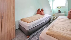 Een knus slaapkamer met een enkel bed, een nachtkastje, een kleine tafel en een kledingkast.
