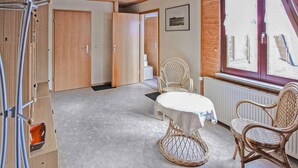 A room with a round table, wicker chairs, a wooden door, and a window with a view. - Ferienwohnung Altenkirchen (Altenkirchen auf Rügen)