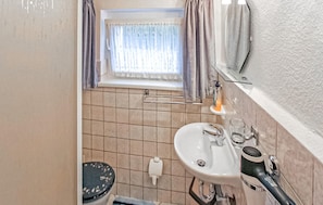 A bathroom with a sink, toilet, and window with curtains. - Ferienwohnung Zirchow (Zirchow)