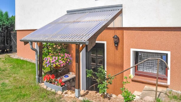 Ein Haus mit überdachter Veranda, einer Tür und einem Fenster mit einer Hinweistafel.