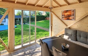 A cozy wooden interior with a large sliding glass door leading to a green lawn and a pool. - Ferienwohnung Neppermin/Usedom (Neppermin/Usedom)