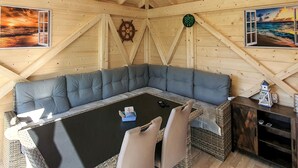 A cozy wooden room with a sectional sofa, a small table, and a wall clock. - Ferienwohnung Neppermin/Usedom (Neppermin/Usedom)