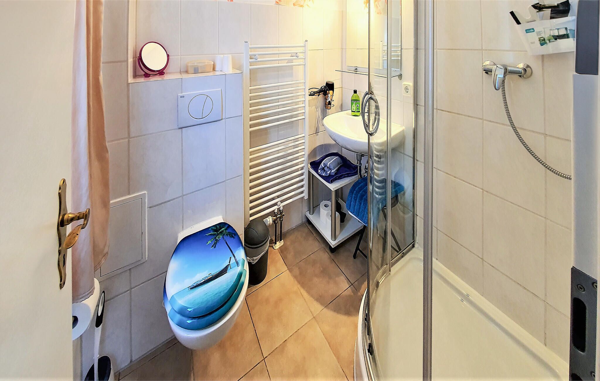 A compact bathroom with a toilet, a sink, a shower, and a towel rack.