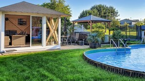 A backyard with a swimming pool, a covered seating area, and a barbecue setup. - Ferienwohnung Neppermin/Usedom (Neppermin/Usedom)