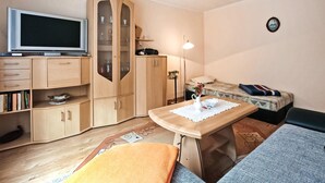 Una habitación pequeña con cama, escritorio, televisor y armario.