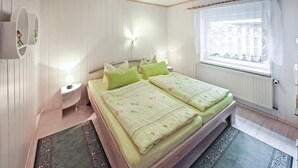 Un dormitorio con una cama doble, dos mesitas de noche, un radiador y un ventanal con vistas.