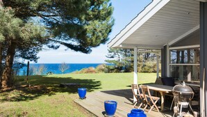 A covered patio with a view of the sea, a barbecue grill, and outdoor seating. - Awesome home in Sjællands Odde (Sjællands Odde)
