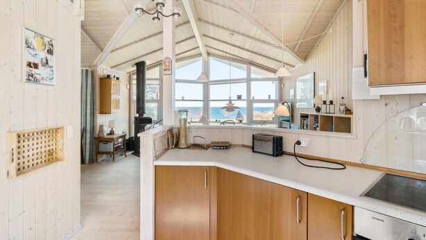 A modern kitchen with wooden cabinets, a Siemens refrigerator, and a large window overlooking the sea. - Awesome home in Sjællands Odde (Sjællands Odde)