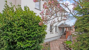 Ein Gartenweg führt zu einem Haus mit einer kleinen Laube und Stufen.
