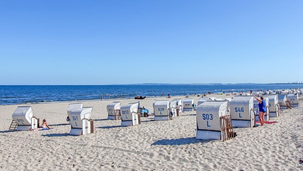 Strandhütten mit den Nummern SL31, SL28, SL12, SL03, SL46 und SL14 an einem Sandstrand mit dem Meer im Hintergrund.