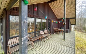 Enjoy outdoor dining or relaxation on the cabin's deck, surrounded by large windows and a sloping roof.