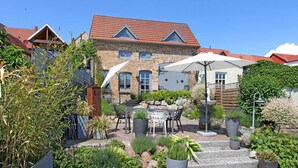 A courtyard with a stone building, outdoor seating, and potted plants. - Ferienhaus Plau am See (Plau am See)