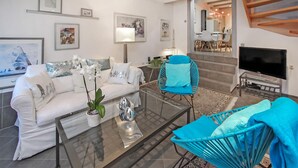 A modern living room with a white sofa, a glass coffee table, a blue chair, and a TV. - Ferienhaus Plau am See (Plau am See)