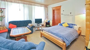 A hotel room with a bed, a sofa, a desk with a computer, a television, and a window with curtains. - Beautiful apartment in Lychen with WiFi (Lychen)