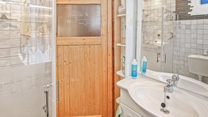 A bathroom with a wooden door, a glass shower enclosure, a white sink, and a mirror. - Beautiful apartment in Lychen with WiFi (Lychen)