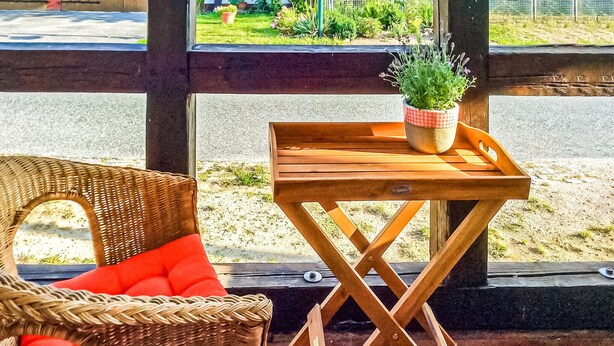 A wicker chair with a red cushion and a small wooden table with a potted plant. - Stunning apartment in Kieve with WiFi (Kieve)