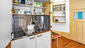 A compact kitchen with a stainless steel sink, white cabinets, and a small countertop. There are shelves above the sink holding dishes and a coffee maker. - Stunning apartment in Kieve with WiFi (Kieve)