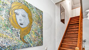 A hallway with a large abstract painting on the wall and a wooden staircase. - Stunning apartment in Kieve with WiFi (Kieve)
