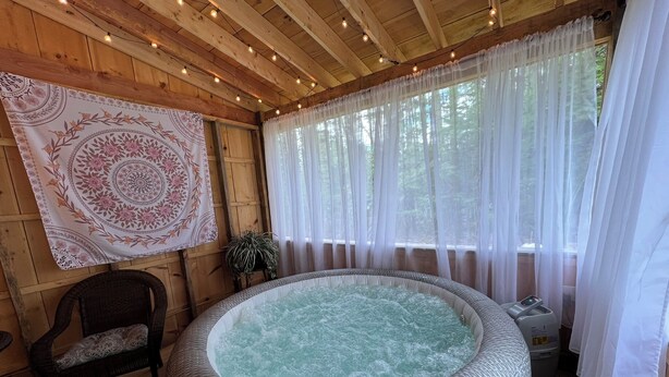 Una cabaña de madera con un jacuzzi, una silla y un tapiz.