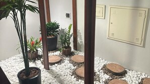Un petit jardin clos, agrémenté de graviers blancs, de jardinières en bois où sont plantées différentes espèces, et d’une structure en bois.