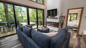 En moderne stue med en stor sofa, pejs og et tv ophængt på væggen.