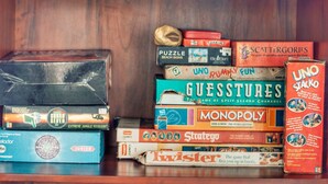 Una colección de juegos de mesa apilados en un estante de madera.