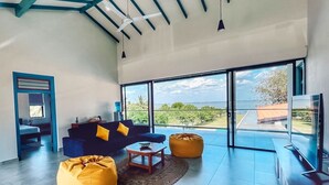 Un salón amplio con un gran ventanal, un sofá, una mesa de centro y una televisión.
