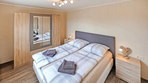 A modern bedroom with a large bed, a wardrobe, a bedside table, and a mirror. - Nice apartment in Mirow with WiFi (Mirow)
