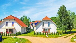 Une rangée de maisons blanches aux toits rouges, alignées de part et d’autre d’un chemin de terre qui les traverse.