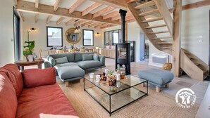 A spacious living room with a modern fireplace, a dining area, and a staircase leading to an upper level. - Villa Valérie - Locmaria (LOCMARIA)