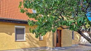 Un bâtiment jaune avec un toit recouvert de tuiles rouges, une porte en bois et une fenêtre.