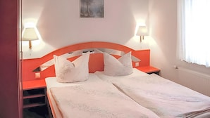 Une chambre d’hôtel avec un lit, deux lampes de chevet, un tableau au mur et une fenêtre avec des rideaux.