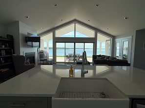 A modern kitchen with a large island, a fireplace, and a view of the water.